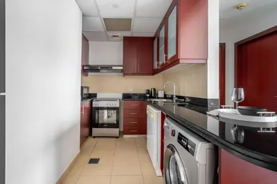 a kitchen with red cabinets and a washing machine at GuestReady - Luxurious Marina view residence in Dubai