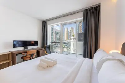 a bedroom with a large white bed with a large window at West Avenue - Chic One Bedroom in Dubai