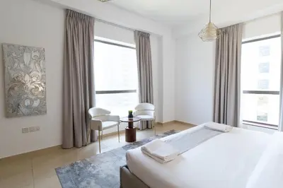 a white bedroom with two chairs and a bed at BAHAR apartments on JBR by HAPPY SEASON in Dubai