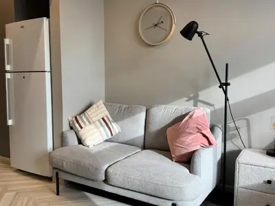a living room with a couch and a clock on the wall at Warm and Elegant Studio in Dubai in Dubai