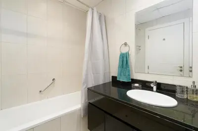 a bathroom with a sink and a mirror and a tub at White Sage - Damac Ghalia JVC 35th Floor with Balcony in Dubai