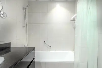 a white bathroom with a tub and a shower at White Sage - Damac Ghalia JVC 35th Floor with Balcony in Dubai