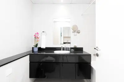 a white bathroom with a sink and a mirror at White Sage - Damac Ghalia JVC 35th Floor with Balcony in Dubai