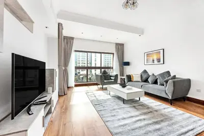 a living room with a couch and a tv at StoneTree - 1BR apartment with Beach Access Fairmont in Palm Jumeirah in Dubai