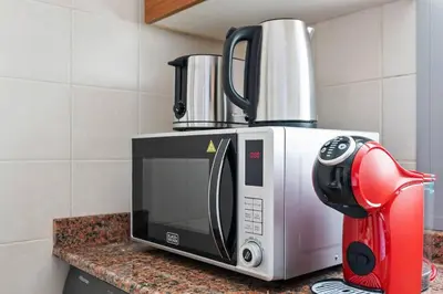 a kitchen counter with a microwave and a red mixer at StoneTree - New Cozy Studio in Dubai Marina in Dubai