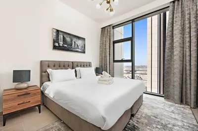 a bedroom with a large bed and a large window at StoneTree - Elegant 1BR in amazing community in Dubai