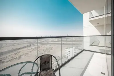 a balcony with a chair and a view of a beach at StoneTree - Cozy 1BR with spacious balcony in Golf Vita A in Dubai