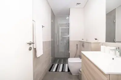 a white bathroom with a toilet and a shower at StoneTree - Cozy 1BR with spacious balcony in Golf Vita A in Dubai