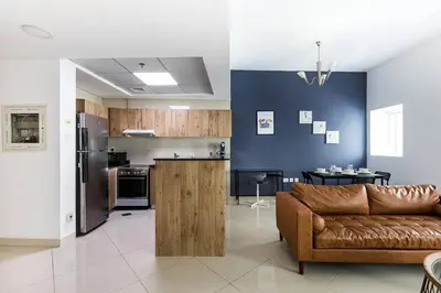 a living room with a brown couch and a kitchen at Tranquil Retreat With Epic Marina View in Dubai