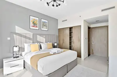 a white bedroom with a large bed and a chandelier at StoneTree - Stylish 1BR & Pool with Burj Khalifa Views in Dubai