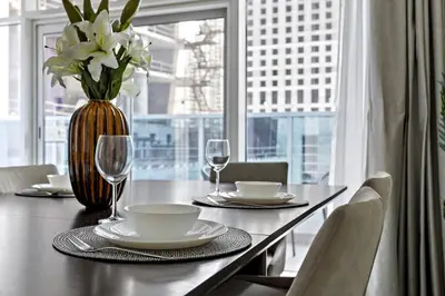 a dining room table with a vase of flowers and glasses at StoneTree - Furnished 2 BR with Maids Room in Dubai Marina in Dubai