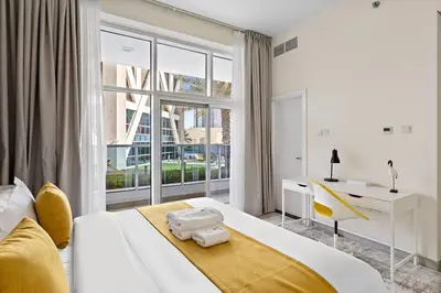 a white bedroom with a large window and a bed at StoneTree - Furnished 2 BR with Maids Room in Dubai Marina in Dubai