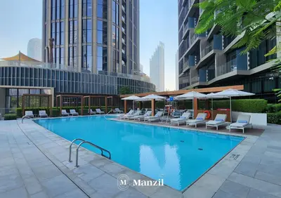 a large swimming pool with chairs and umbrellas at Address Opera - Lux 3 BR with Full Burj Khalifa View near Dubai Mall in Dubai