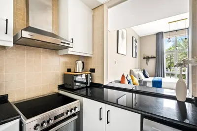a kitchen with white cabinets and a black counter top at Luxury apartment at Discovery in Dubai