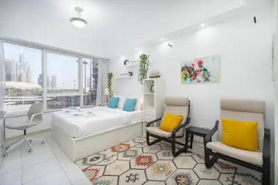 a bedroom with a bed and two chairs and a window at Cozy Haven with Spiritual Charm in JLT in Dubai