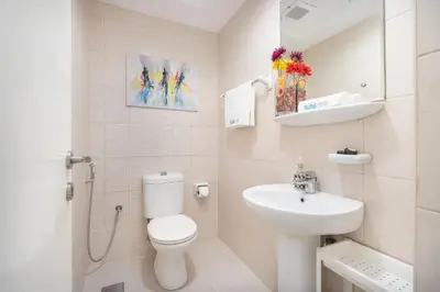 a white bathroom with a toilet and a sink at Cozy Haven with Spiritual Charm in JLT in Dubai