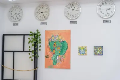 a wall with clocks and a painting on a wall at Cozy Haven with Spiritual Charm in JLT in Dubai