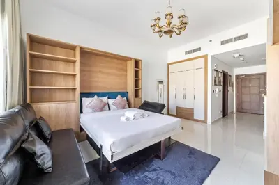 a bedroom with a bed and a couch and a chandelier at StoneTree - Modern Style of Studio in Resortz by Danube in Dubai