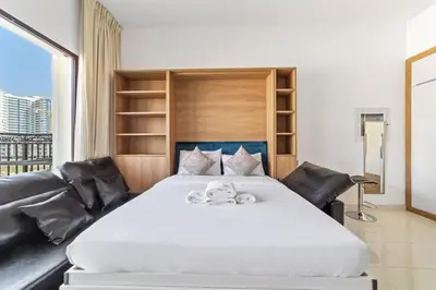 a bedroom with a large white bed with leather furniture at StoneTree - Modern Style of Studio in Resortz by Danube in Dubai