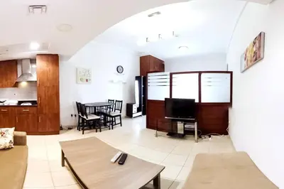 a living room with a couch and a table at StoneTree - Furnished Studio with Lake View and near Metro in Dubai