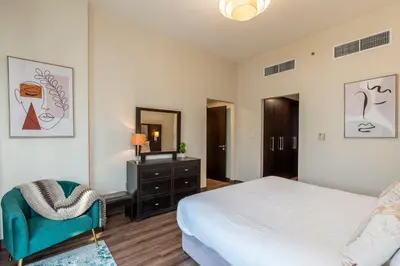 a bedroom with a bed and a chair and a dresser at BEAUTIFUL HUGE 2 BED ROOM APARTMENT in Dubai