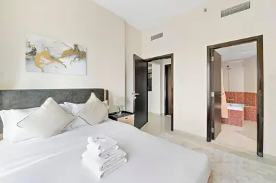a bedroom with a white bed with two towels on it at StoneTree - Elegant 1 BR with Amazing View in Dubai