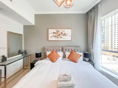 a bedroom with a large white bed with orange pillows at StoneTree - Furnished 1BR near Marina Walk in Dubai