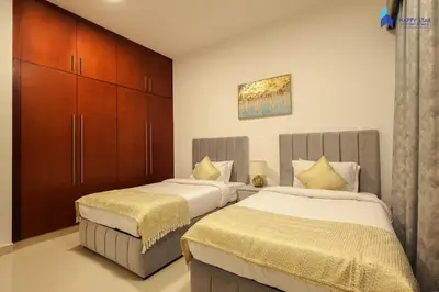 a bedroom with two beds and a cabinet at Stylish 2BR Suite Near MOE in Dubai