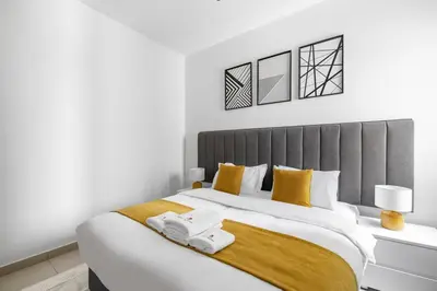 a white bedroom with a large bed with yellow pillows at StoneTree - Homelike 1BR in Dubai Marina in Dubai