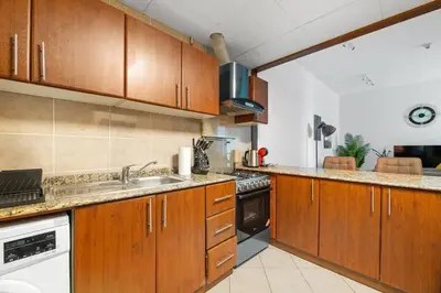a kitchen with wooden cabinets and a sink at StoneTree - Homelike 1BR in Dubai Marina in Dubai