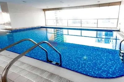 a large swimming pool with blue water in a building at Daniels Spacious 1BR in Heart of Dubai Marina in Dubai