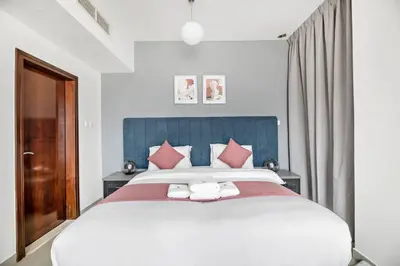 a bedroom with a large white bed with red pillows at StoneTree - Stylish 1BR in JLT in Dubai
