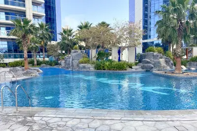 a large swimming pool in a city with palm trees at ALiving Supreme 3BR I Paramount Towers, Business Bay- 6104 in Dubai