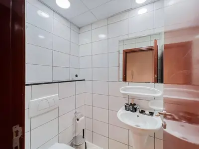 a white bathroom with a sink and a toilet at StoneTree - Modern 1 BR Apartment Near The Beach in Dubai