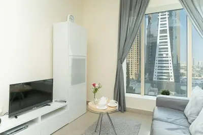 a living room with a couch and a large window at StoneTree - Chic Studio in Jumeirah Lake Towers in Dubai