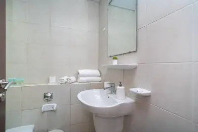 a white bathroom with a sink and a mirror at StoneTree - Chic Studio in Jumeirah Lake Towers in Dubai