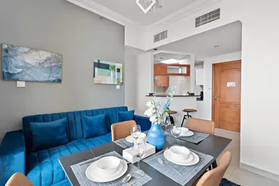 a living room with a blue couch and a table at StoneTree - Stylish 1BR near Marina Walk in Dubai
