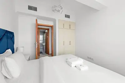a white bedroom with a white bed with a phone on it at StoneTree - Stylish 1BR near Marina Walk in Dubai