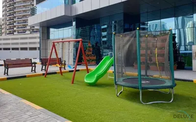 a playground with a slide and a swing at Ritzy 1BR at Global Golf Residence 2 Sports City by Deluxe Holiday Homes in Dubai