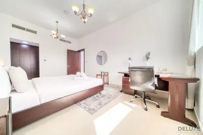 a bedroom with a bed and a desk and a chair at Ritzy 1BR at Global Golf Residence 2 Sports City by Deluxe Holiday Homes in Dubai
