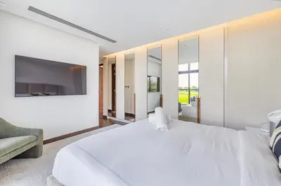 a white bedroom with a large bed and a tv at Daniels 5BR Villa with Private Pool at Damac Hills in Dubai