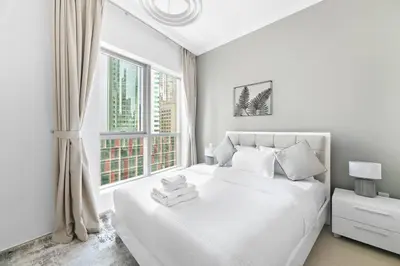 a white bedroom with a white bed and a window at StoneTree - Furnished 1 BR in Bay Central in Dubai