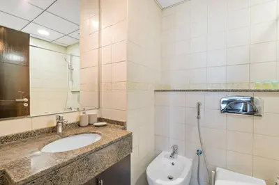 a bathroom with a sink and a toilet and a mirror at StoneTree - Furnished 1 BR in Bay Central in Dubai