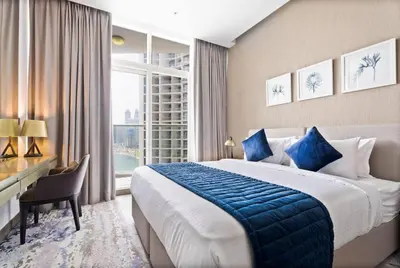 a hotel room with a bed and a desk and a window at Phineek Homes Luxury Studio With Canal View Damac Maison Prive Business Bay in Dubai