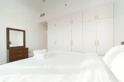 a white bedroom with white cabinets and a mirror at StoneTree - Fully Furnished 1BR near Metro Station in Dubai