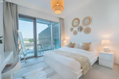 a white bedroom with a bed and a balcony at Downtown Views II Tower 1 brand new units in Dubai
