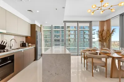 a kitchen with a table and a dining room with windows at Your beachfront luxe escape experience - Suiteable in Dubai