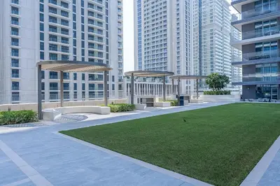 a park with benches and grass in front of tall buildings at Your beachfront luxe escape experience - Suiteable in Dubai
