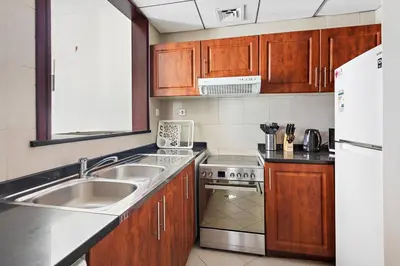 a kitchen with wooden cabinets and a sink and a refrigerator at StoneTree - Elegant Studio in Peaceful Community in Dubai