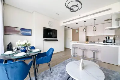 a kitchen and living room with a table and chairs at Modern Style 1 BR near Marina Mall and Metro in Dubai